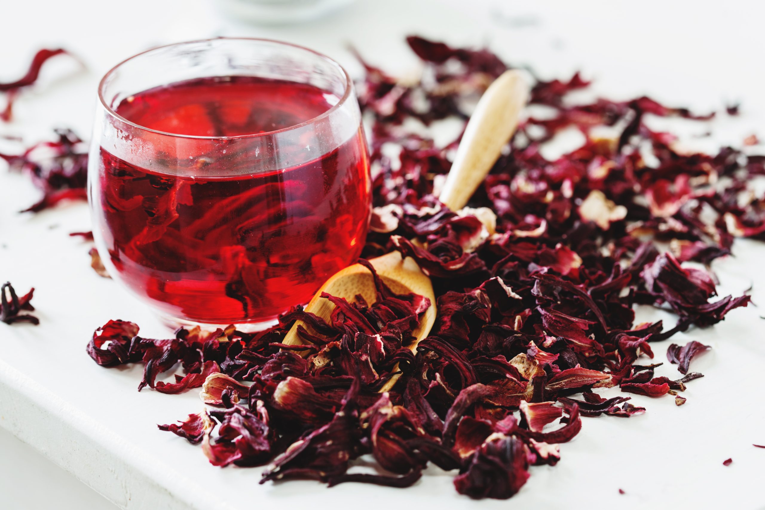 Hibiscus tea in a cup with alongside hibiscus flowers