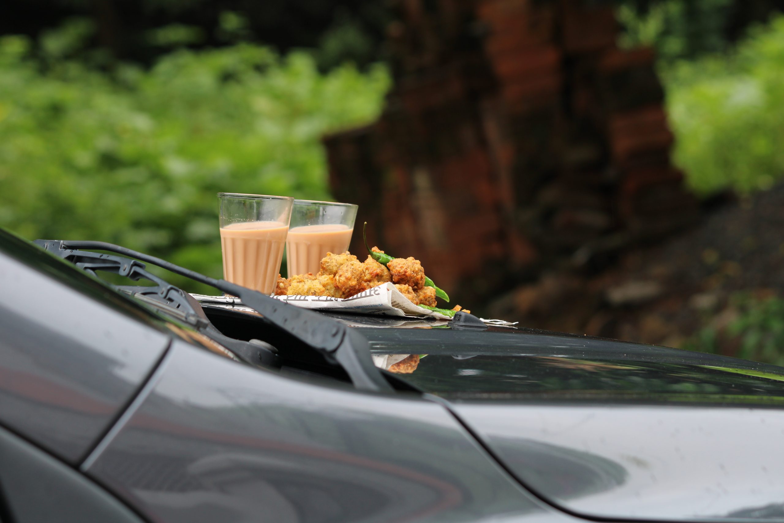 Crispy pakoras, delicious street food, favourite indian snack in monsoon served with Hot Tea. Kept on car's bonnet.