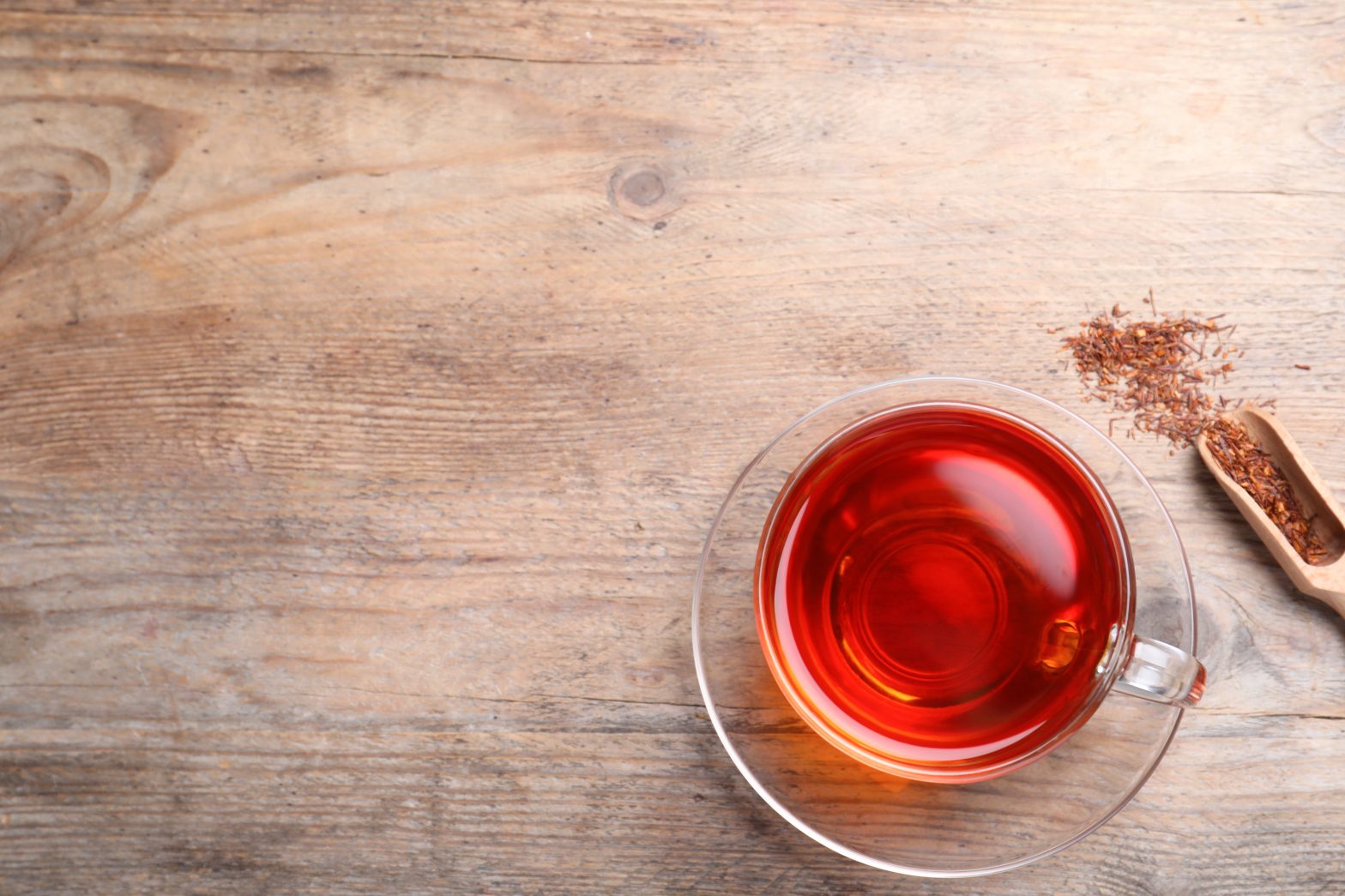 Freshly brewed rooibos tea and dry leaves on wooden table