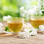 cups of jasmine tea and fresh jasmine flowers on a wooden table