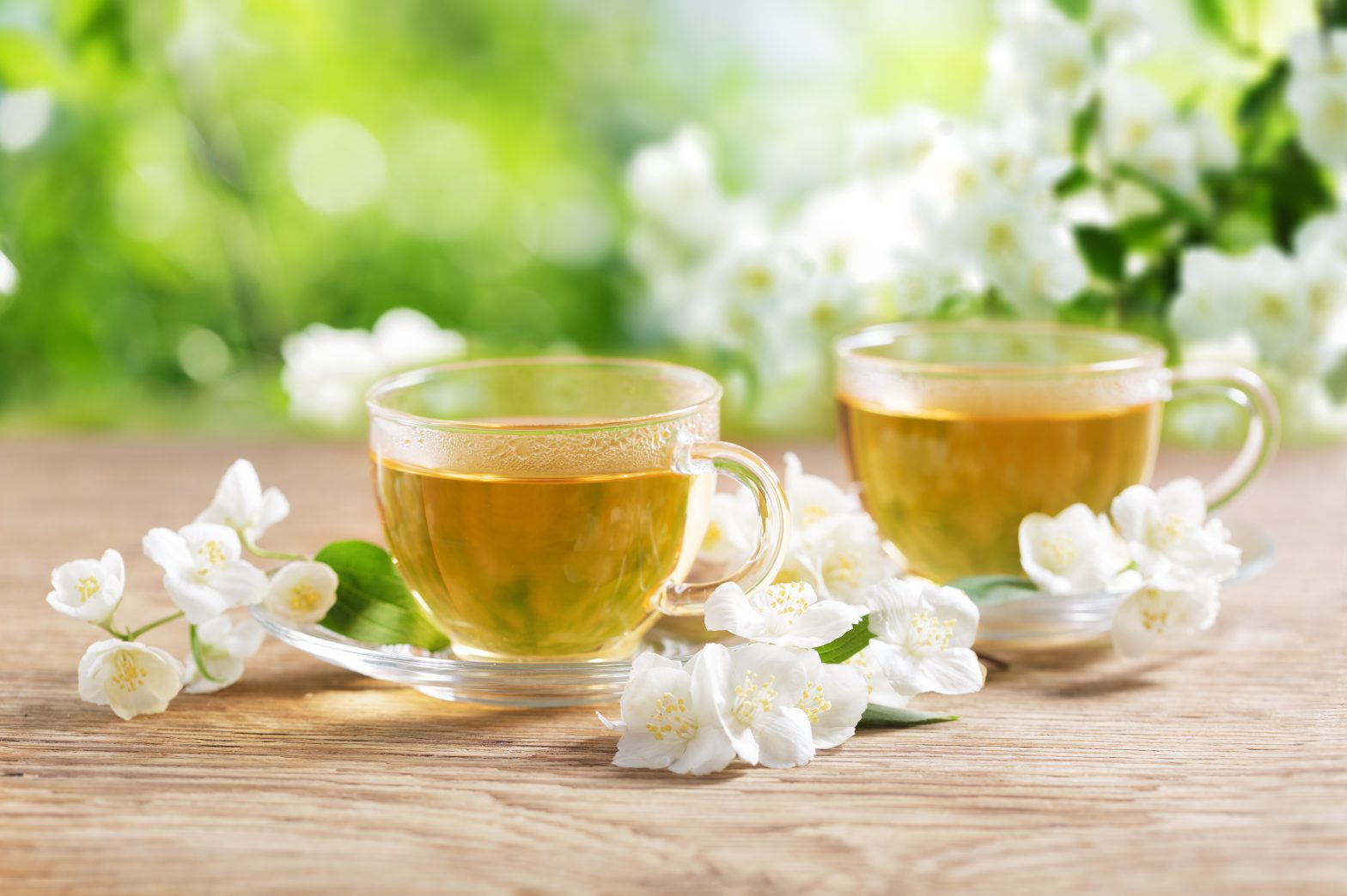 cups of jasmine tea and fresh jasmine flowers on a wooden table