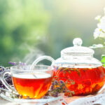 Cup with hot darjeeling tea with mint and a thyme on a wooden table