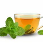 A glass cup of refreshing Decaffeinated tea with fresh mint leaves on a white background